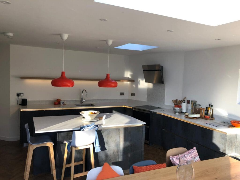 Kitchen extension with skylight, dark cabinetry and orange pendant lights above the island