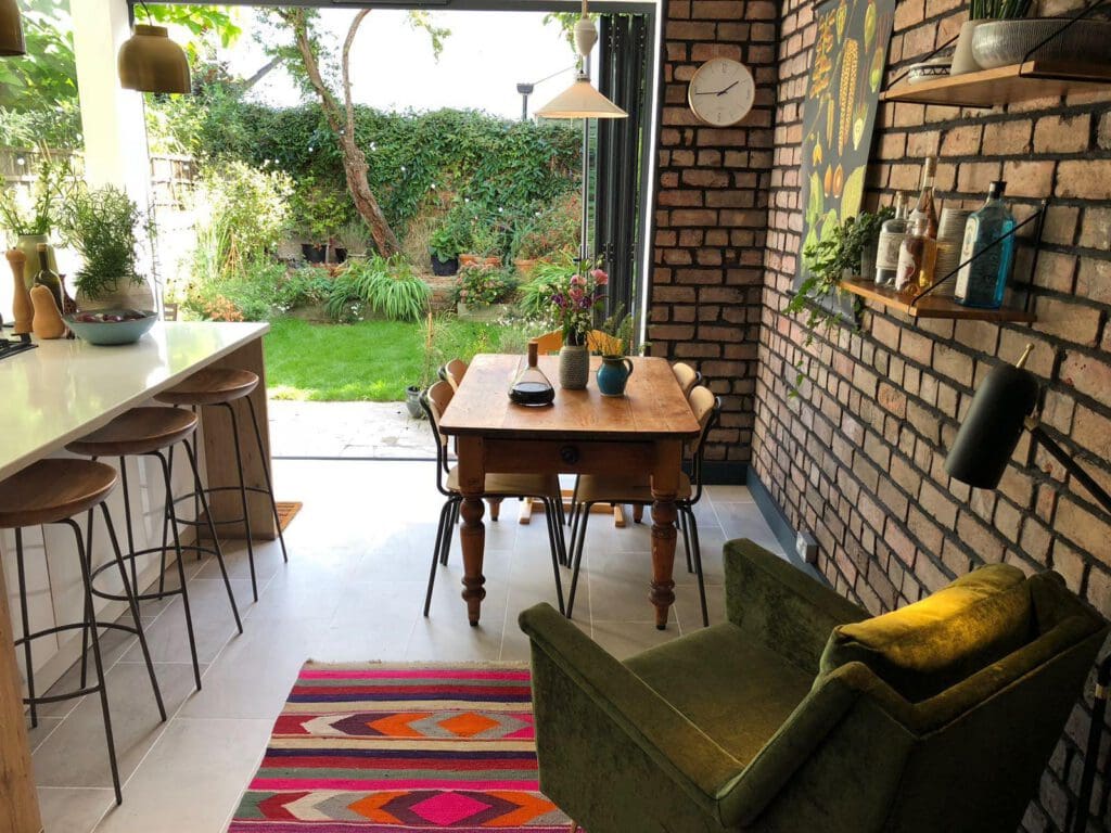 Brick-walled kitchen diner with open glass doors leading to a lush Bristol garden
