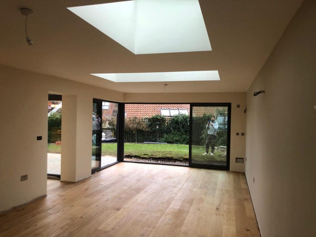 Empty finished room with wooden flooring, floor-to-ceiling glazing and skylights