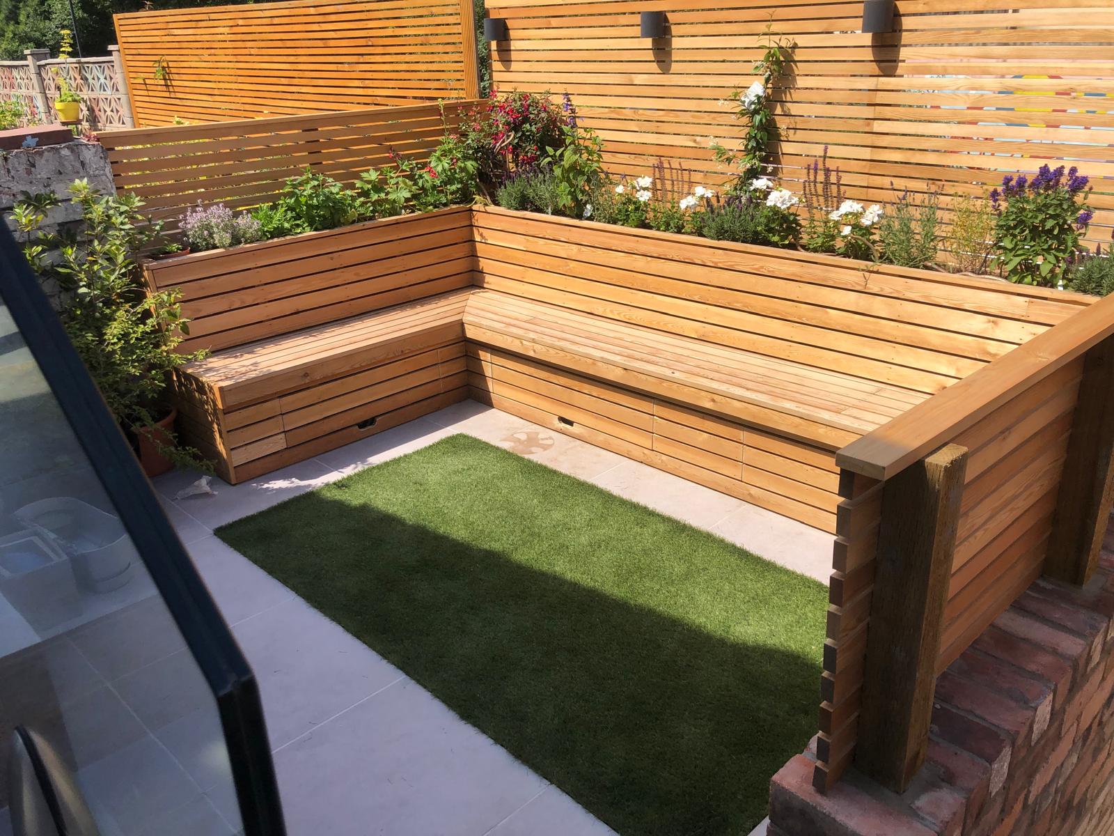 Modern garden seating area with L-shaped wooden benches and slatted fencing